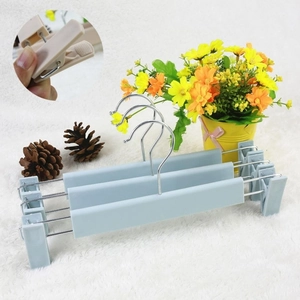 Adjustable light blue plastic pant hangers with metal hooks on a white plush rug