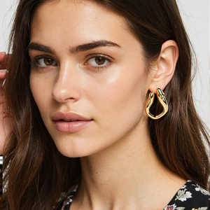 Minimalist geometric twisted stainless steel earrings plated in 18k gold on model