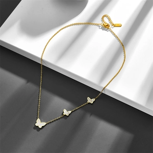 Elegant gold butterfly necklace with shell pendants on a modern aesthetic background