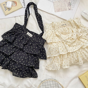 Detailansicht von gestuften Rüschen-Tote-Bags in Schwarz und Creme mit Blumenmustern