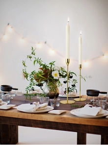 Elegant gold plated metal candlesticks set on a romantic dinner table with warm lighting