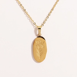 Macro shot of gold stainless steel oval pendant featuring delicate rose flower engraving