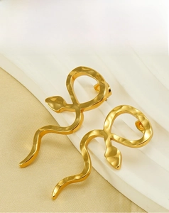 Gros plan de boucles d'oreilles serpent dorées avec texture martelée élégante
