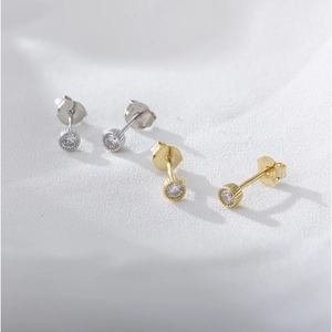 Macro detail of silver and gold s925 studs with round zircon in gear setting