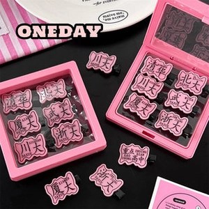 Detailed view of pink university-themed hair clips in matching jewelry display boxes