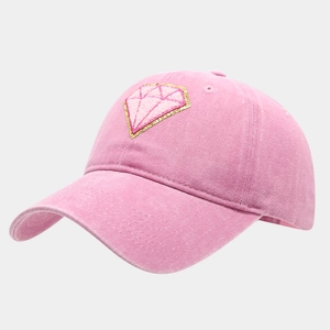 Close-up of pink cotton baseball cap featuring a diamond-shaped embroidery patch on the front