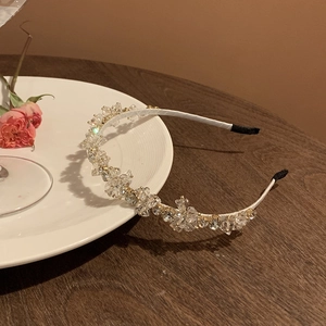 Dettaglio del cerchietto con cristalli scintillanti e filo dorato su seta bianca
