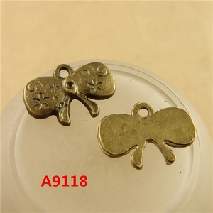 Detailed close-up of antique bronze alloy bow charms for DIY jewelry making with floral patterns