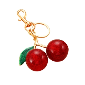 Sparkly red cherry keychain with green glitter leaf and gold metal lobster clasp on white background