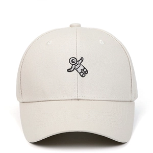 Detailed close-up of astronaut embroidery on a beige cotton baseball cap front