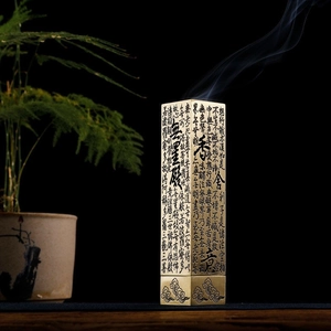 Macro detail of vertical brass incense burner with Heart Sutra calligraphy engraving