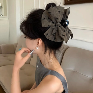 Large fabric bow claw clip with grey-brown floral print shown on a model hair side view