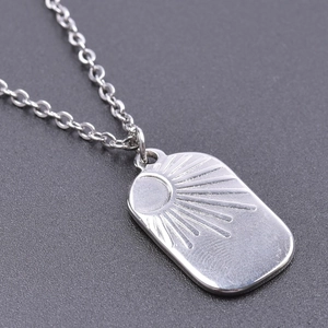 Macro view of silver sunburst rectangular pendant with polished stainless steel texture