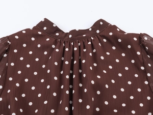 Dettaglio del tessuto in chiffon marrone a pois con elegante colletto alla coreana pieghettato