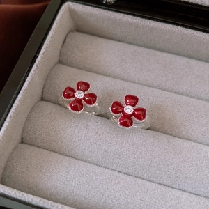 Detailed macro view of red enamel flower earrings with silver borders and zircon centers