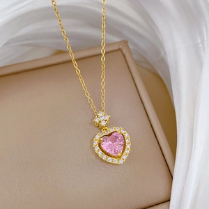 Close-up of pink heart gemstone necklace with pavé crystal halo on beige display