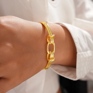 Close-up of 18K gold-plated oval knot open bangle on model's wrist with minimalist style