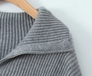 Close-up of grey knit sweater collar featuring a half-zip metal zipper and ribbed texture