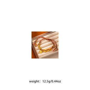 Detail view of woven red cord bracelet with golden coins on a jewelry display tray
