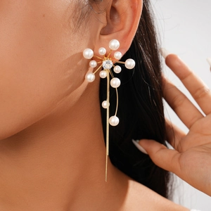 Close-up of gold tassel earrings with zircon center and radial faux pearl floral design