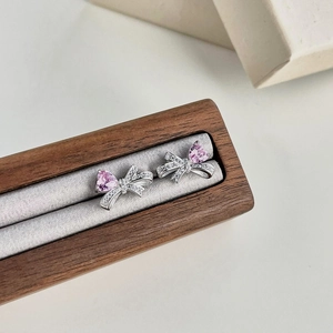 Detail view of heart-shaped pink zircon stud earrings with silver bowknot design
