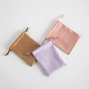 Detail of colorful suede flannel jewelry pouches with drawstring in brown, purple, and pink