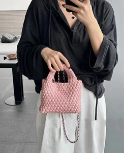 Detailed view of pink woven mini bucket bag with chain strap shown on a model