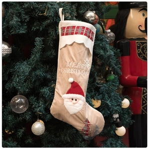 Close-up of a rustic beige Santa Christmas stocking with plush details on a tree