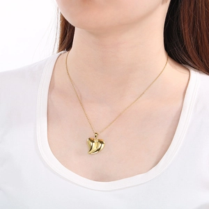 Close-up of a polished gold heart pendant necklace worn on a female model's neck