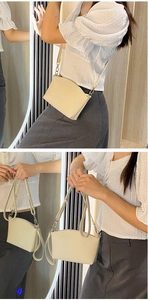 Detail of cream white leather crossbody bag with silver zipper and adjustable strap