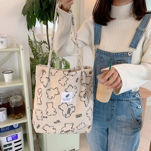Detail of beige corduroy tote bag with bear print in a casual cafe lifestyle setting