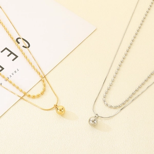 Vue rapprochée de colliers double rang en or et argent avec pendentifs perles rondes
