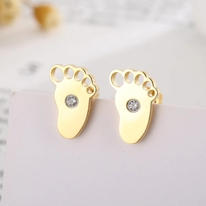 Macro shot of gold-toned baby footprint stud earrings with sparkling center zirconia