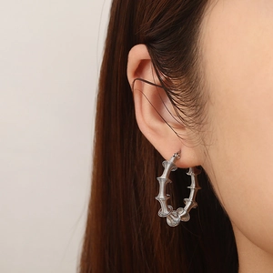 Silver hollow bamboo spring C-shaped stainless steel earrings shown on a model's ear