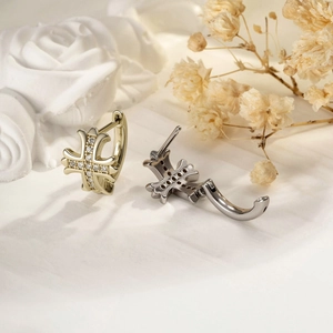 Elegant gold and silver cross hoop earrings with zircon stones on a floral background