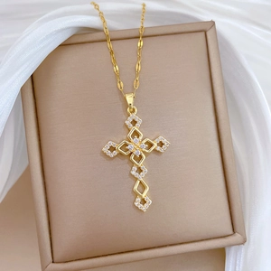 Close-up of golden cross necklace with sparkling cubic zirconia on white silk
