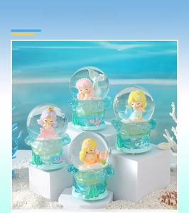 Detail view of cartoon mermaid crystal balls with LED lights and coral-textured bases