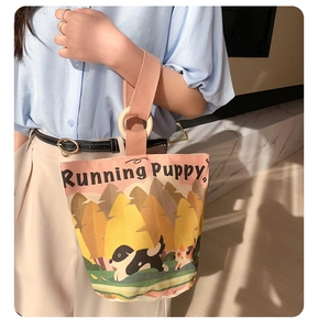 Detail of canvas bucket bag with pink strap featuring puppy illustration in sunlight