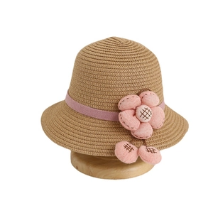 Kids summer straw sun hat with pink fabric flower and ribbon on a wooden stand