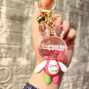 Close-up of acrylic rabbit keychain with pink liquid glitter and golden bell detail