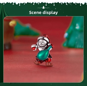 Detail of S925 silver Santa Claus charm with green enamel gift bag on red festive background