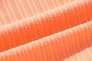 Macro detail of breathable ribbed polyester fabric in vibrant salmon orange color