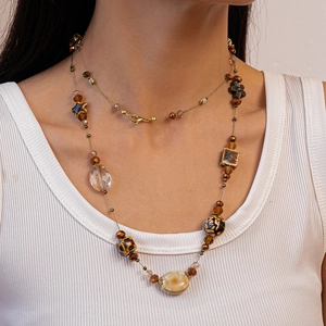 Close-up of bohemian beaded necklace with earthy glass charms on woman's collarbone