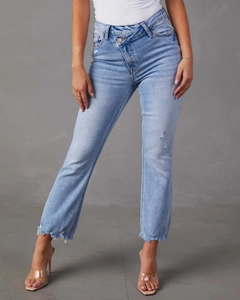 Dettaglio dei jeans azzurri con vita a bottoni incrociati ed effetto strappato usurato
