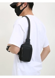 Rear view of a black waterproof mini chest bag worn by a model against a white background