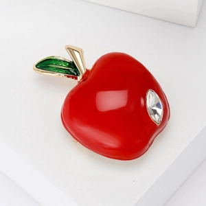 Red apple heart brooch with gold leaf and sparkling rhinestone on a white pedestal