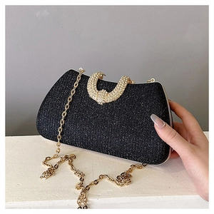 Detail of black glitter clutch bag with gold chain and curved rhinestone metal buckle