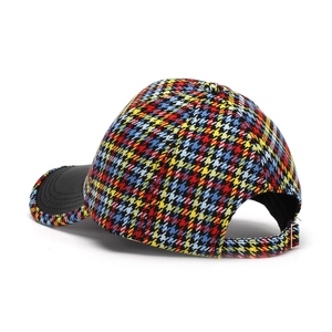Detail of adjustable metal buckle and black leather brim on colorful houndstooth baseball cap