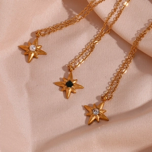 Detailansicht von drei goldenen Sternanhängern mit Perlen und Edelsteinen auf Satin