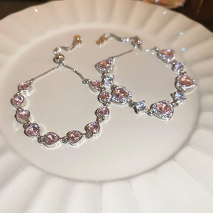 Detail of heart-shaped pink zircon bracelets with adjustable sliding clasp on a white plate